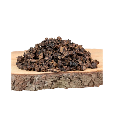 Haufen kleiner, dunkelbrauner, unregelmäßig geformter Stücke auf einer Holzscheibe mit Rinde