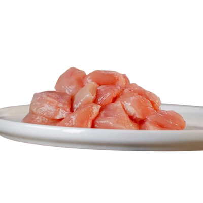 Rohes, gewürfeltes Hühnerfleisch auf einem weißen Teller, etwa 1 kg, für die Tierernährung, von der Marke Barfgold.