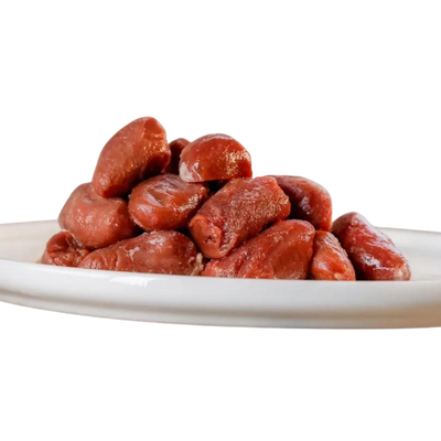 Eine weiße Platte mit einer hohen Menge an rohen Hühnerherzen, die glänzend und frisch aussehen. Die Herzen sind in einer unregelmäßigen Form angeordnet.