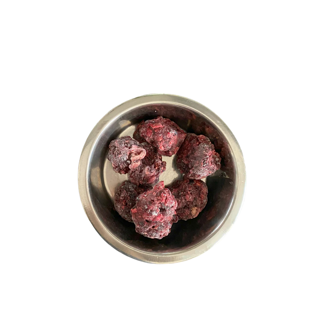 Metallnapf mit mehreren gefrorenen, dunkelroten Fleischnuggets