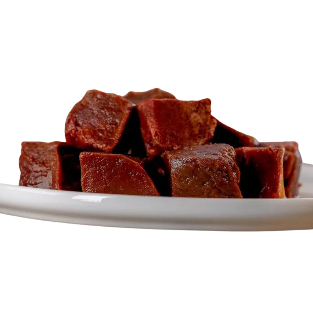 Stücke von Barfgold Pferdeherz auf einem weißen Teller. Die Stücke sind dunkelbraun und haben eine würfelförmige Form.