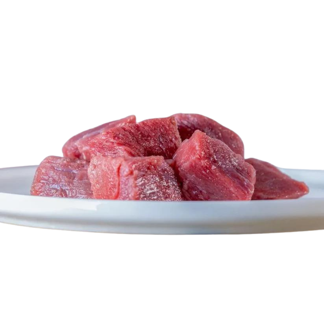 Mehrere rohe Rindfleischwürfel auf einem weißen Teller, naturbelassen und frisch geschnitten – ideal geeignet für die BARF-Ernährung