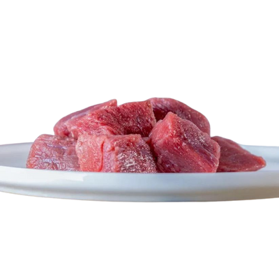 Mehrere rohe Rindfleischwürfel auf einem weißen Teller, naturbelassen und frisch geschnitten – ideal geeignet für die BARF-Ernährung