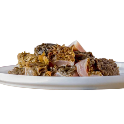 Barfgold Rinderpansen auf einem weißen Teller, in unregelmäßigen Stücken, mit einer groben, faserigen Textur.