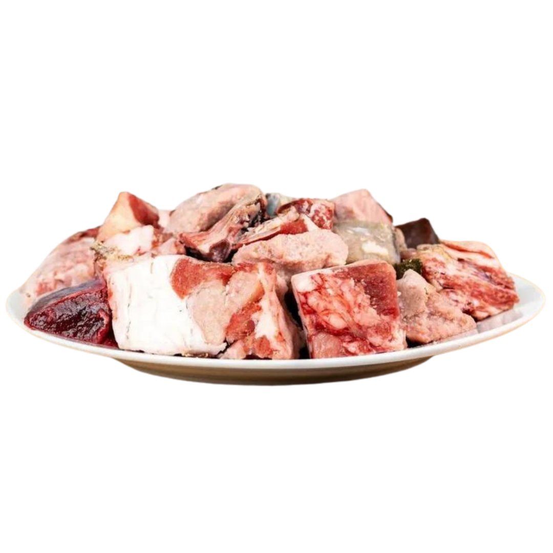 Ein Teller mit rohem Lammfleisch, einschließlich Knochen und Fleischstücken in verschiedenen Formen und Größen.