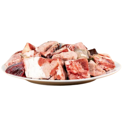 Ein Teller mit rohem Lammfleisch, einschließlich Knochen und Fleischstücken in verschiedenen Formen und Größen.