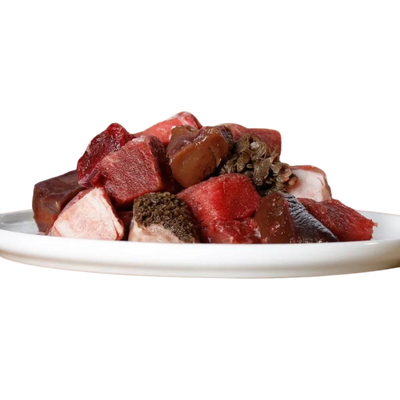 Eine weiße Platte mit einer Mischung aus rohem Rindfleisch in verschiedenen Formen und Größen, darunter Stücke mit Fett und Innereien.