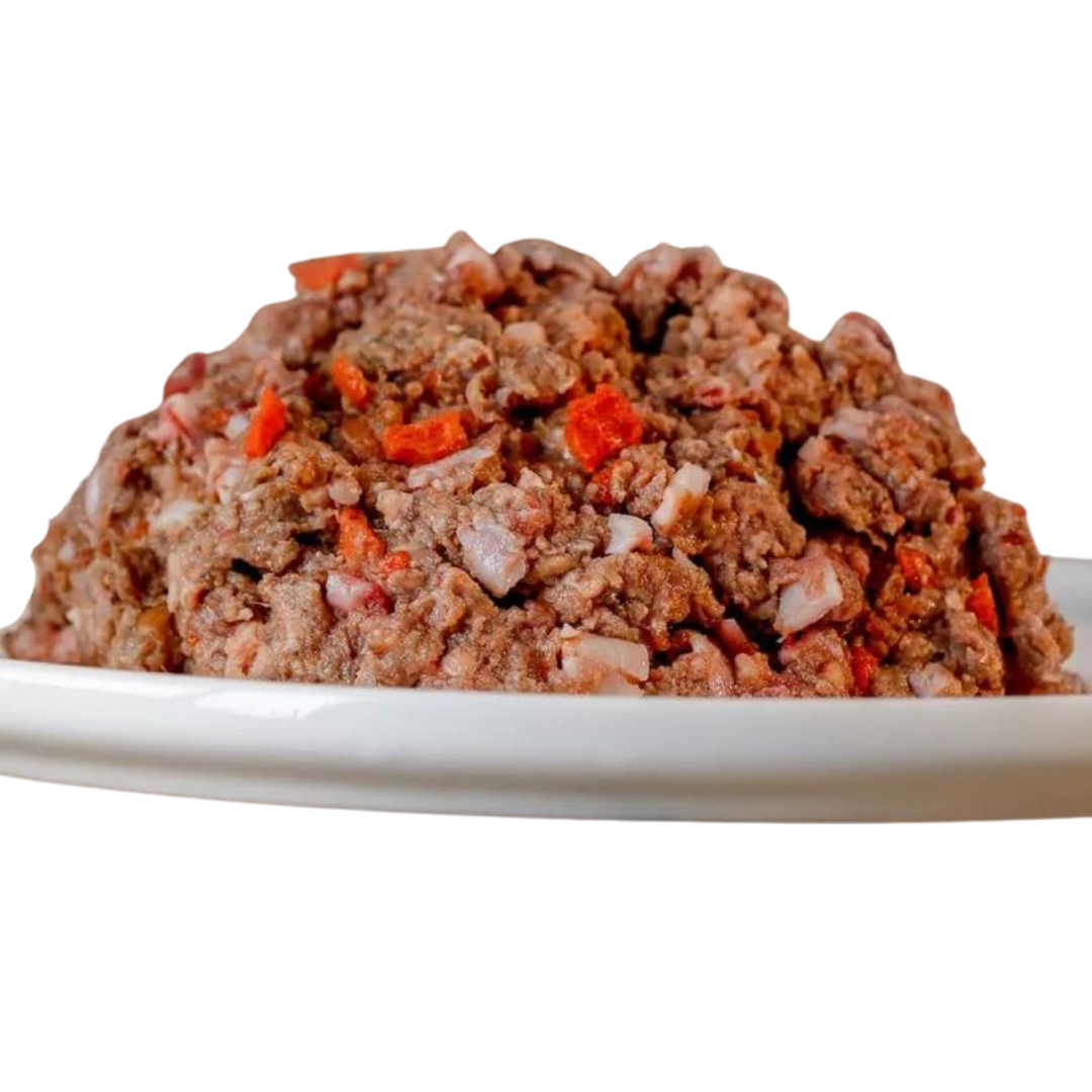 Barfgold Komplett Menü Rind, 1 kg, auf einem weißen Teller. Das Futter ist gewolft und enthält kleine Stücke von rotem Gemüse.