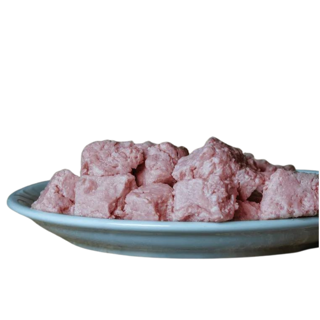 Barfgold Lammknochenmus in einer weißen Schüssel, bestehend aus rosa, würfelförmigen Stücken. Die Stücke sind unregelmäßig geformt und liegen übereinander.