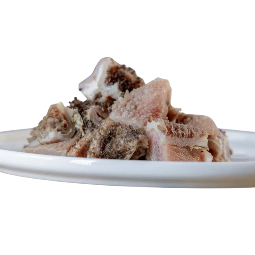 Stücke von Lamm-Pansen auf einem weißen Teller. Die Fleischstücke sind unregelmäßig geformt und zeigen eine Mischung aus hellen und dunklen Bereichen.