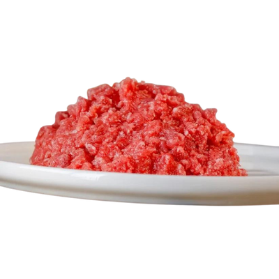 Rote, gewolfte Kaninchenfleischmasse auf einem weißen Teller. Die Masse hat eine grobe, krümelige Textur.