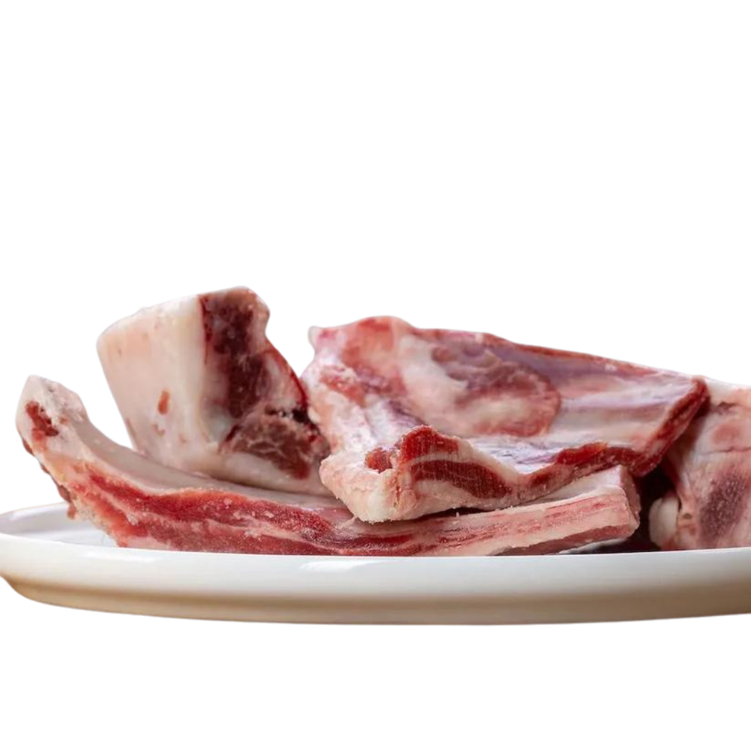 Weißer Teller mit Ziegenrippen. Man sieht die Knochen und das Fleisch. Marke Barfgold