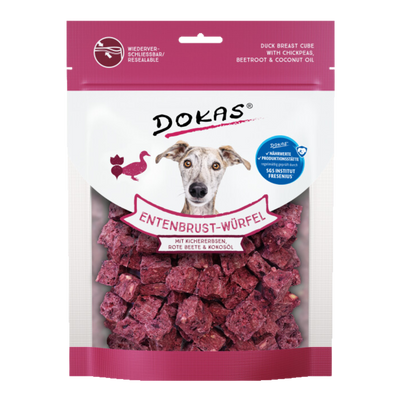 Verpackung von 'DOKAS Entenbrust-Würfel' mit einem Bild eines Hundes, der direkt in die Kamera schaut. Die Verpackung zeigt lila Würfel, die aus Entenbrust, Kichererbsen, roter Beete und Kokosöl bestehen.
