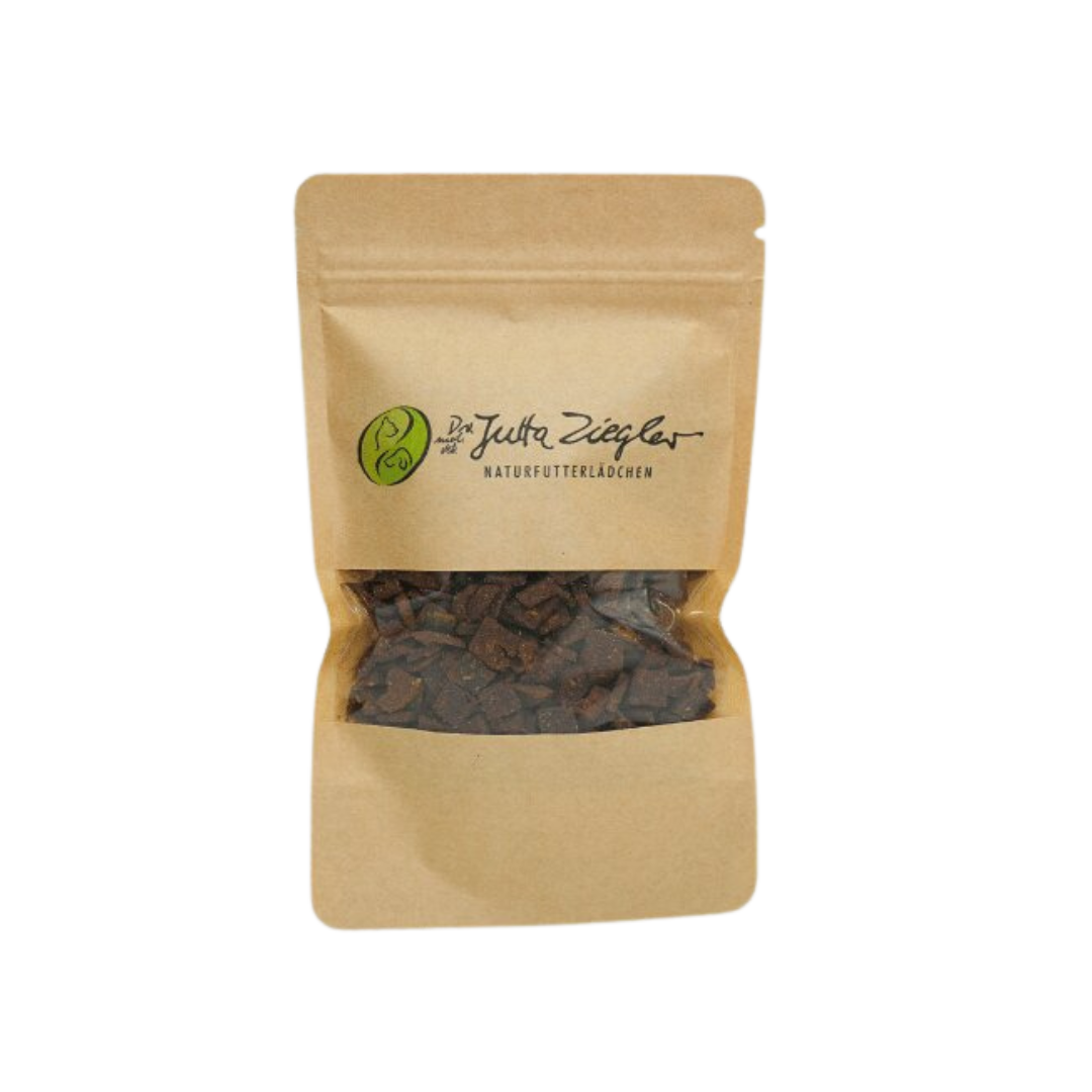 Braune Papiertüte mit transparentem Fenster, gefüllt mit kleinen, dunklen Snacks. Auf der Tüte steht 'Das ist Jutta Ziegler NATURFUTTERLÄDCHEN'.