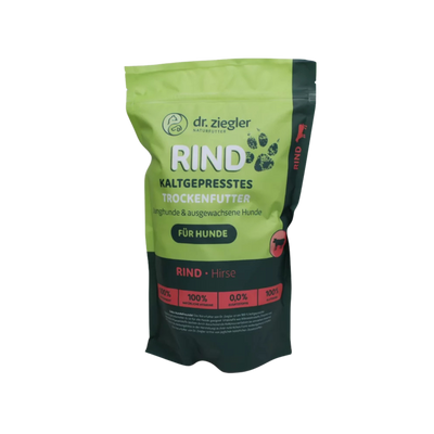 Grünes und schwarzes Futterbeutel mit Aufschrift 'dr. ziegler NATURFUTTER RIND KALTGEPRESSTES TROCKENFUTTER für Hunde' und Symbolen von Pfoten und Hund.
