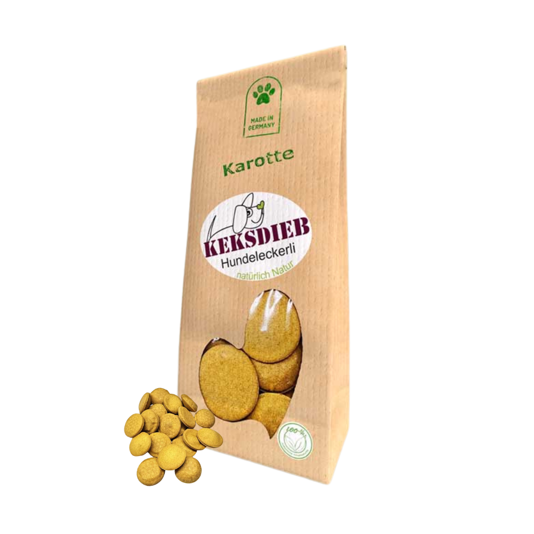 Papiertüte mit der Aufschrift 'Keksdieb Hundeleckerli Karotte', gefüllt mit runden Hundekeksen, die vor der Tüte liegen.
