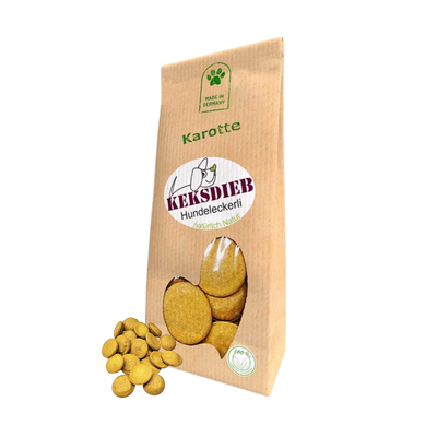 Papiertüte mit der Aufschrift 'Keksdieb Hundeleckerli Karotte', gefüllt mit runden Hundekeksen, die vor der Tüte liegen.