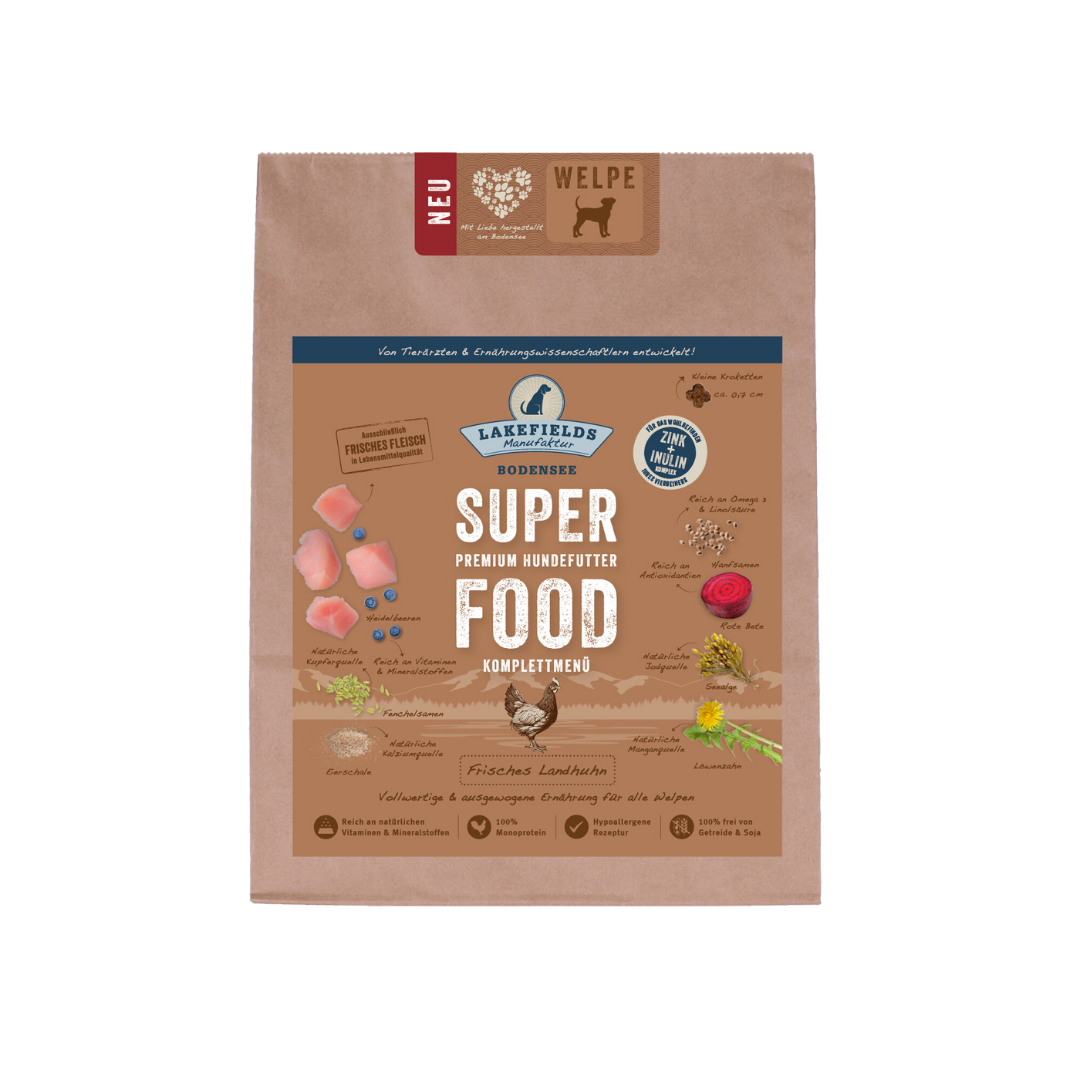 Verpackung von Lakefields Superfood für Hunde, 2.5 kg. Braune Tüte mit Bildern von Landhuhn, Kräutern und dem Text 'NEU' und 'WELPE'.