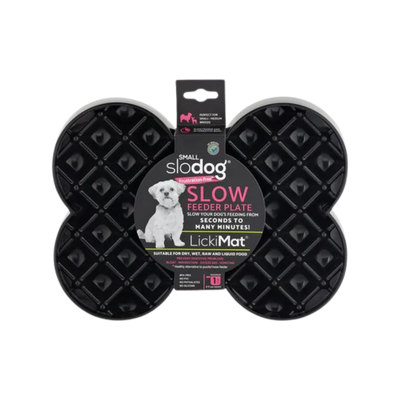 Schwarze Futterplatte 'LickiMat Slodog' in Form eines Knochens mit rautenförmigen Vertiefungen. Verpackung zeigt einen Hund und Informationen zur Verwendung.