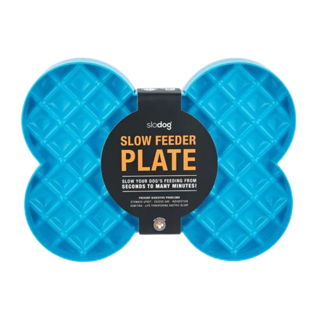 Blaue Futterplatte 'LickiMat Slodog' in Form eines Knochens mit rautenförmigen Vertiefungen. Verpackung zeigt einen Hund und Informationen zur Verwendung.