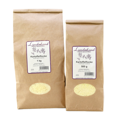 Zwei braune Papiertüten mit Futter. Links die größere Tüte mit 'Lunderland Kartoffelflocke 1 kg', rechts die kleinere mit 'Lunderland Kartoffelflocke 500 g'.