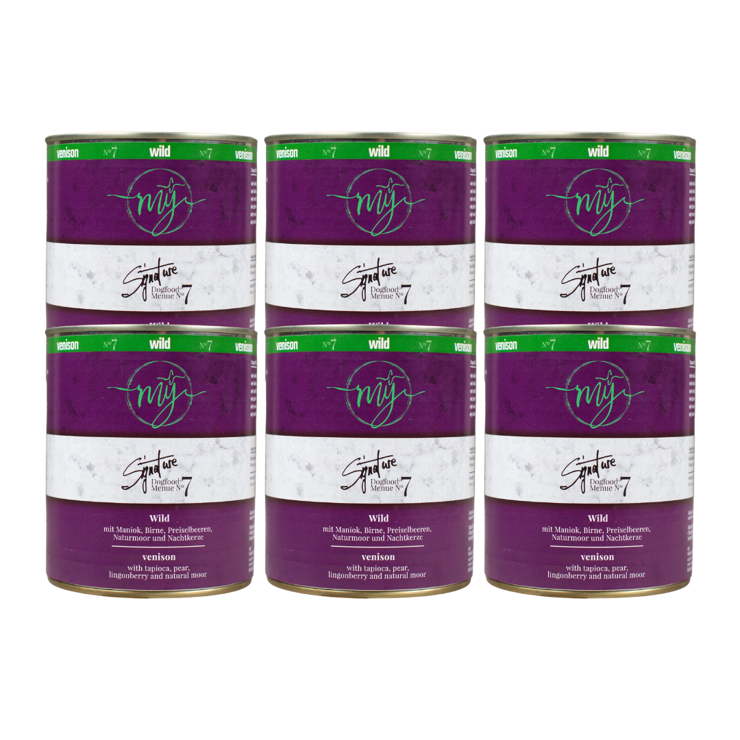 Sechs Dosen Hundefutter mit dunklem violetten Etikett. Aufschrift: my Signature, Dogfood Menue No.7, Wild und Zutaten wie Maniok, Birnen, Preiselbeeren, Naturmoor, Nachtkerze