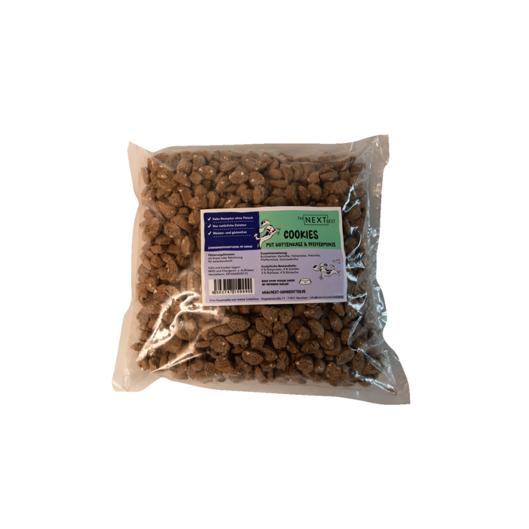 Transparente Verpackung mit 500 g Cookies von der Marke 'NEXT'. Die Cookies haben eine unregelmäßige Form und sind braun. Auf der Vorderseite befindet sich ein Etikett mit Produktinformationen.