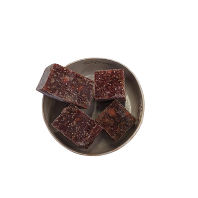 Vier fast quadratische Stücke gemischtes Lammwürfel auf einem grauen, rundem Teller.