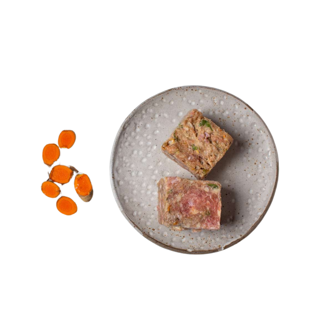 Zwei quadratische Stücke gemischtes Hackfleisch auf einem grauen, rundem Teller neben mehreren geschnittenen Karottenscheiben.