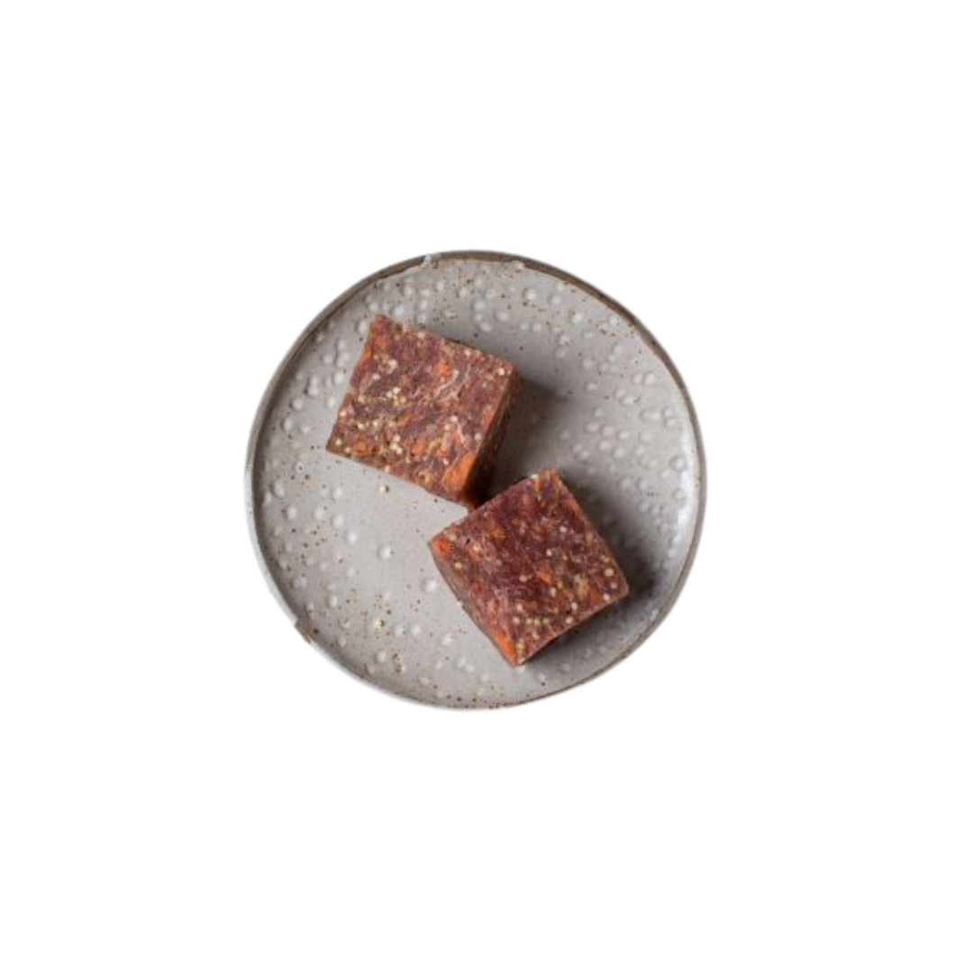 Zwei quadratische Stücke gemischtes Fleischwürfel auf einem grauen, rundem Teller.