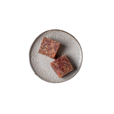 Zwei quadratische Stücke gemischtes Fleischwürfel auf einem grauen, rundem Teller.