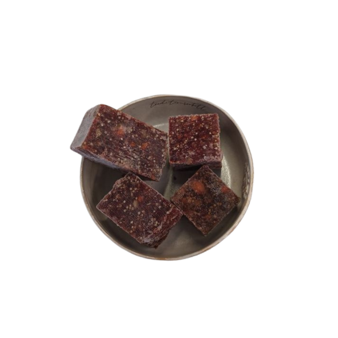 Vier fast quadratische Stücke gemischtes Fleischwürfel auf einem grauen, rundem Teller.