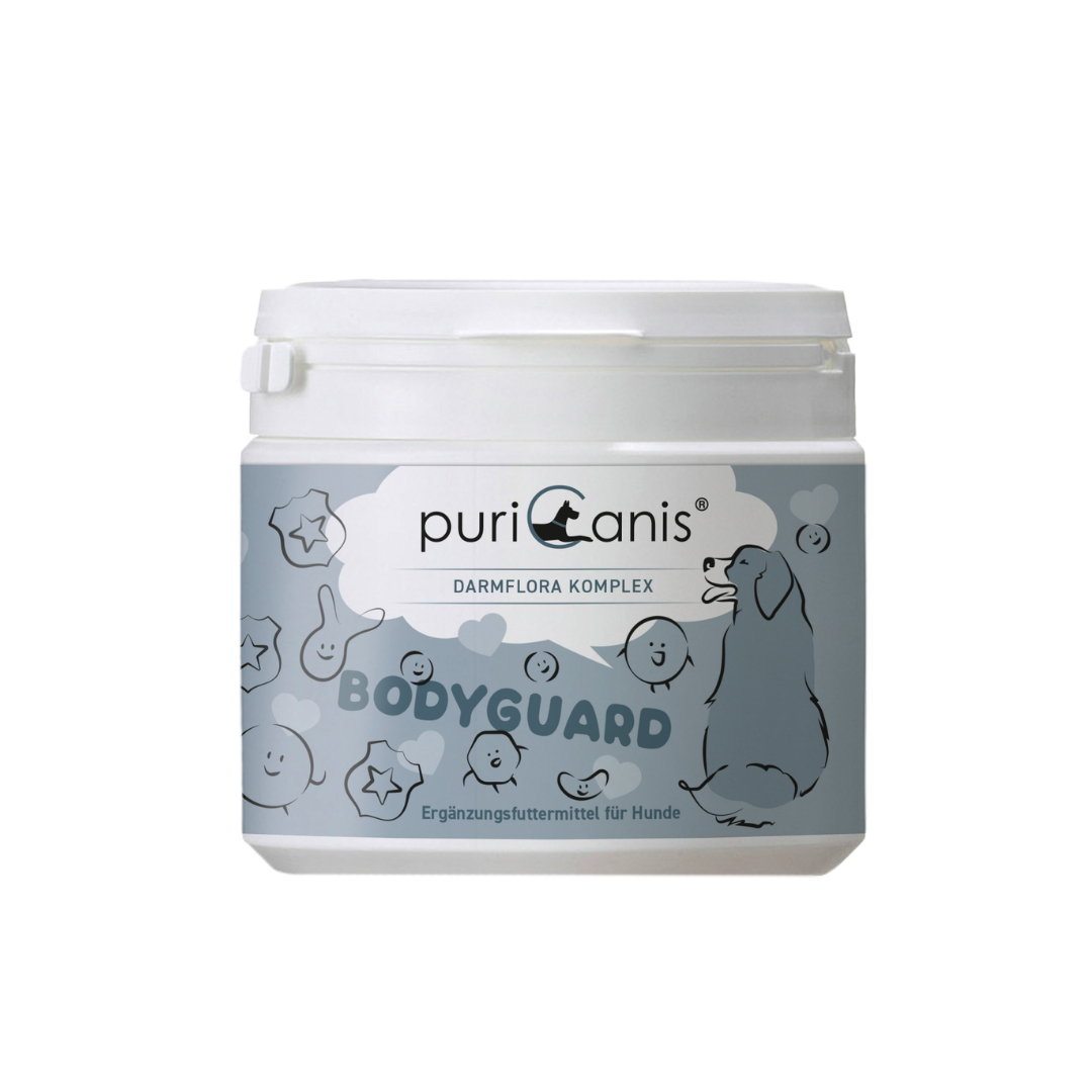 Weißer Behälter mit Aufschrift 'puriCanis DARMFLORA KOMPLEX BODYGUARD Ergänzungsfuttermittel für Hunde' und Zeichnung eines sitzenden Hundes sowie verschiedener lachender und lächelnder Gesichter und Sterne