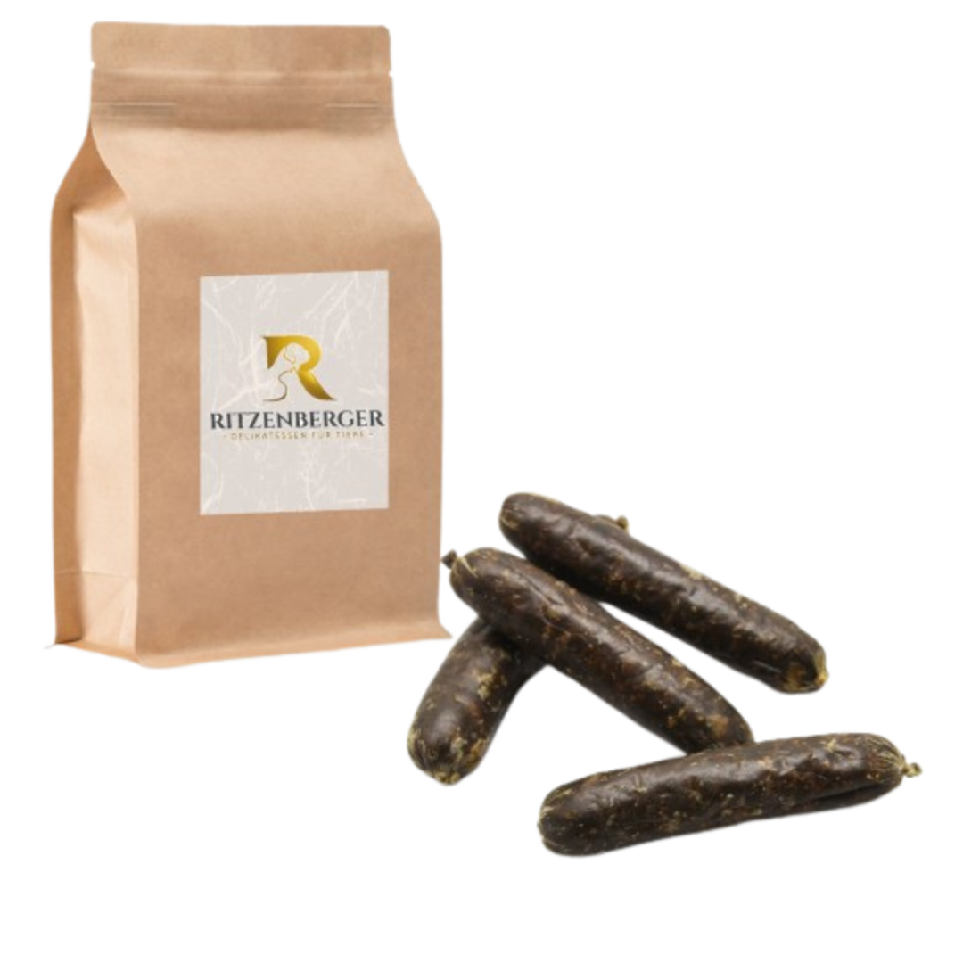 Braune Papiertüte mit Aufkleber 'Ritzenberger' neben vier dunkelbraunen, länglichen Würsten.