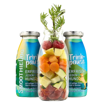 Zwei Flaschen SmoothieDog Trinkpause mit Ente, Obst und Gemüse, davor Glasflasche mit geschnittenem Obst, Gemüse, Himbeeren und Rosmarinzweig.