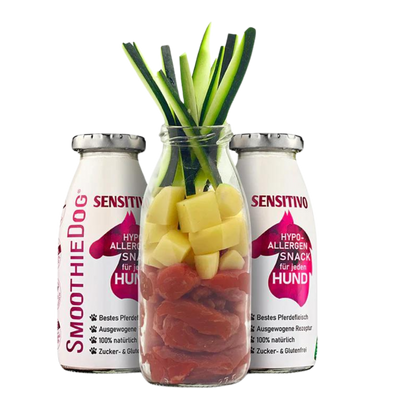 Zwei Flaschen SmoothieDog Trinkpause mit Pferd, Obst und Gemüse, davor Glasflasche mit geschnittenem Obst und Gemüse
