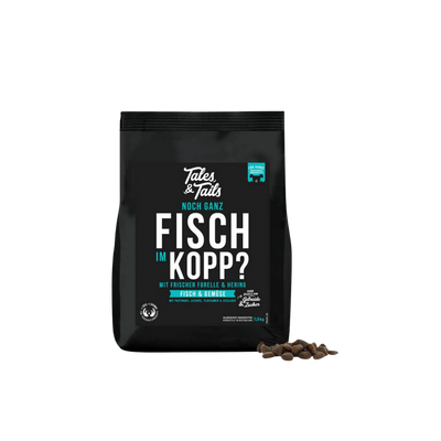 Schwarze Verpackung von Tales & Tails halbfeuchtem Trockenfutter mit der Aufschrift 'Noch ganz Fisch im Kopp', daneben einige braune Futterstücke.