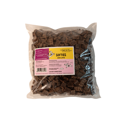 Transparente Verpackung mit 500 g Softies von der Marke 'NEXT'. Die Softies haben eine unregelmäßige Form und sind braun. Auf der Vorderseite befindet sich ein Etikett mit Produktinformationen.