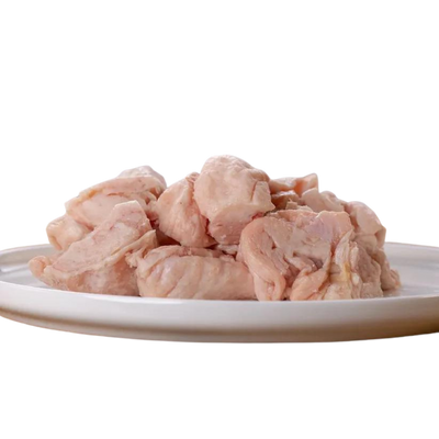 Rohes, gewürfeltes Hühnerfett auf einem weißen Teller. Die Stücke sind hellrosa und ungewürzt.