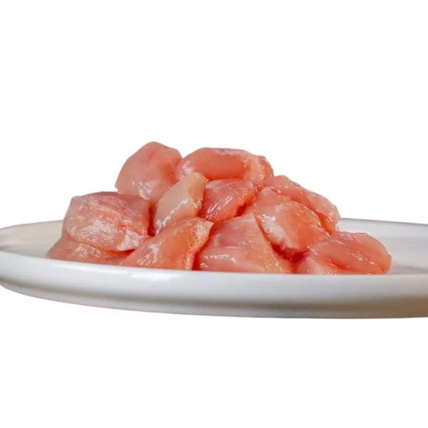Rohes, gewürfeltes Hühnerfleisch auf einem weißen Teller, etwa 1 kg, für die Tierernährung, von der Marke Barfgold.