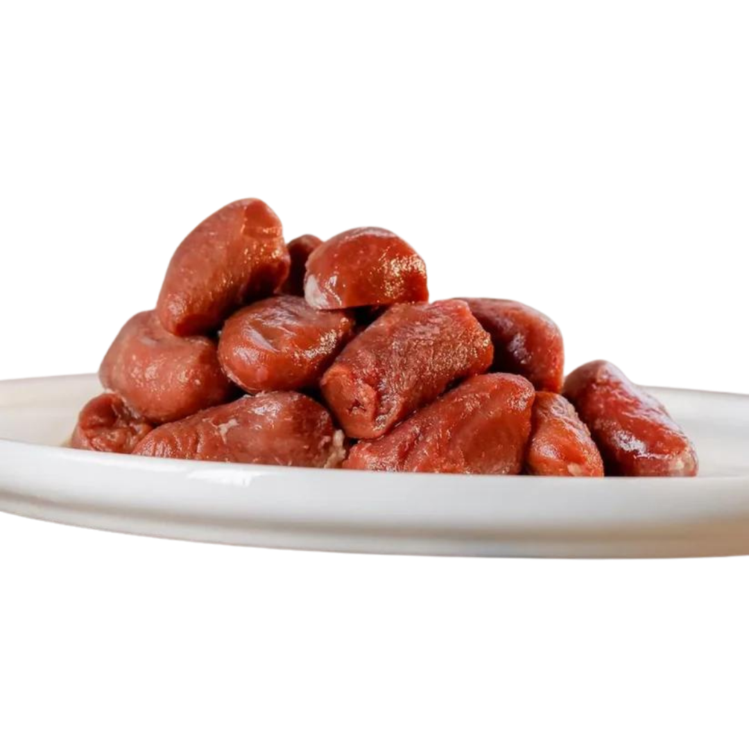 Eine weiße Platte mit einer hohen Menge an rohen Hühnerherzen, die glänzend und frisch aussehen. Die Herzen sind in einer unregelmäßigen Form angeordnet.