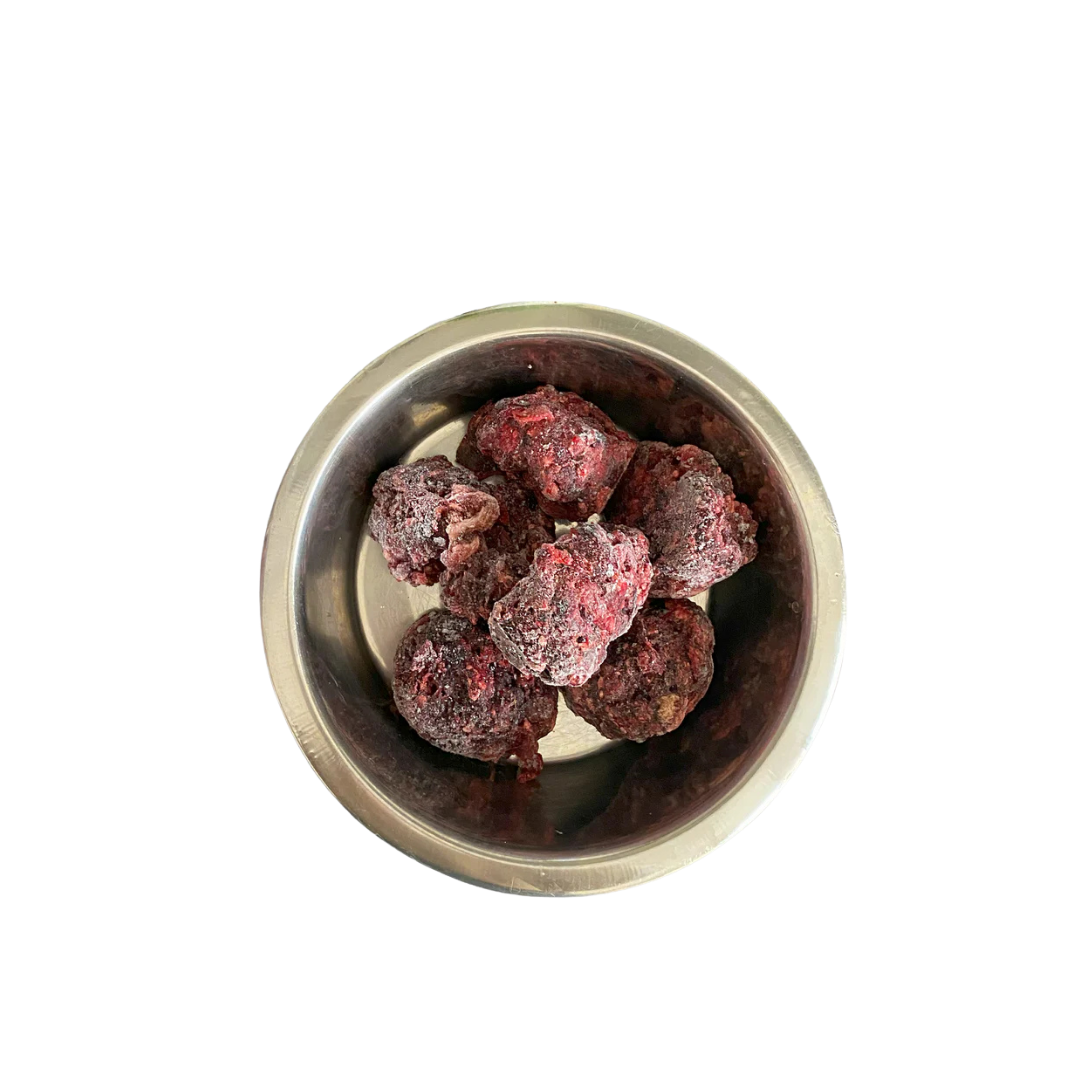 Metallnapf mit mehreren gefrorenen, dunkelroten Fleischnuggets