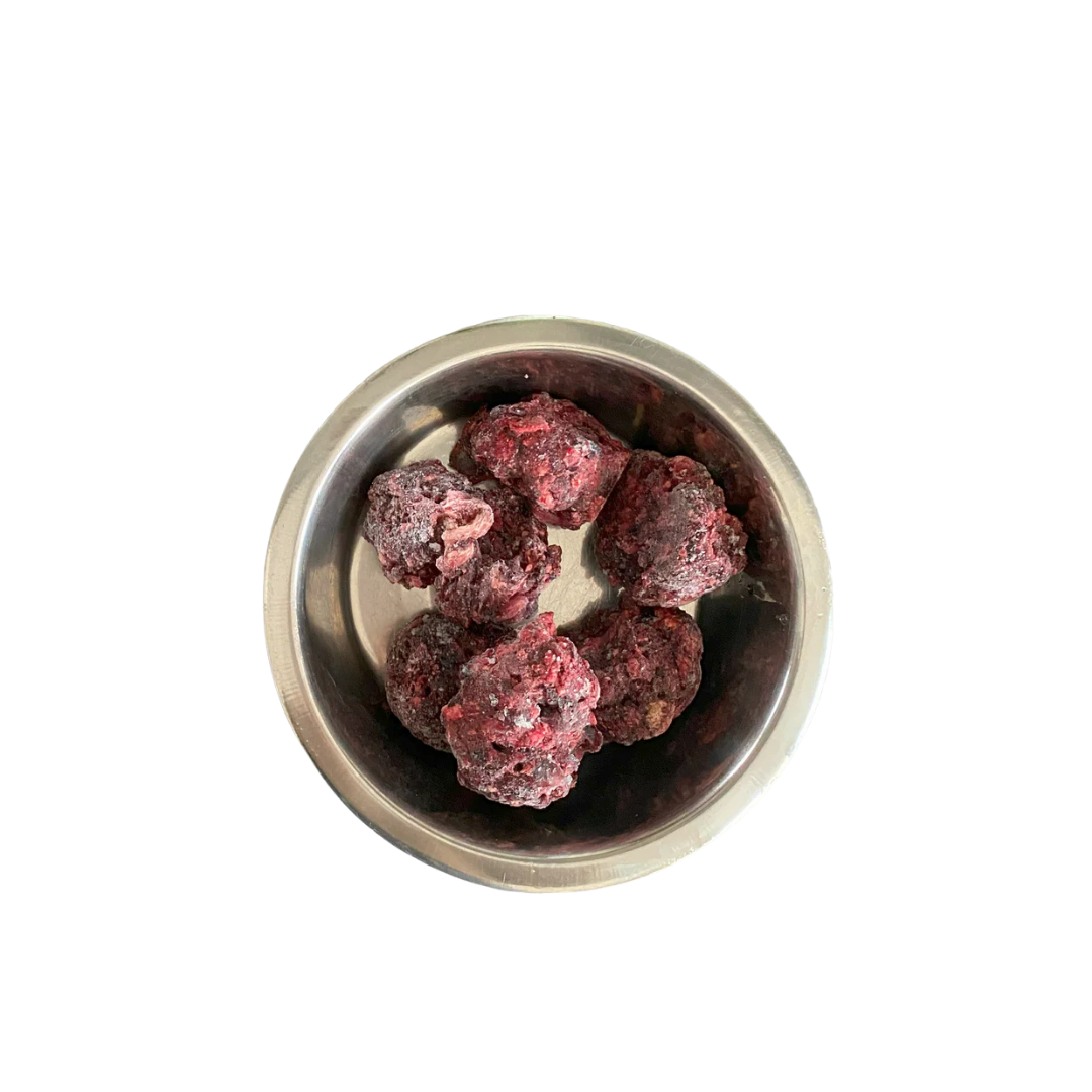 Metallnapf mit mehreren gefrorenen, dunkelroten Fleischnuggets