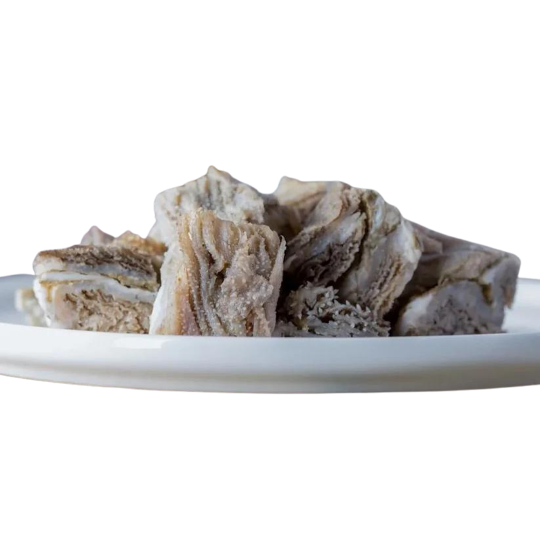 Stücke von getrocknetem Rindermagen auf einem weißen Teller. Die Stücke sind unregelmäßig geformt und zeigen eine schichtartige Struktur.