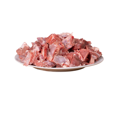 Ein Teller mit magerem Lammfleisch in Würfeln, sichtbar in verschiedenen Formen und Größen. Die Fleischstücke sind rot und rosa.