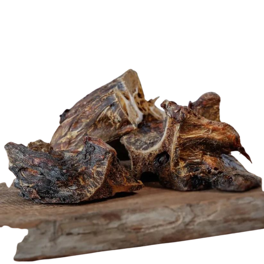 Getrocknete Pferdenackenknochen von Barfgold, in unregelmäßigen Formen auf einem Holzbrett angeordnet. Dunkelbraun mit rauer Oberfläche.