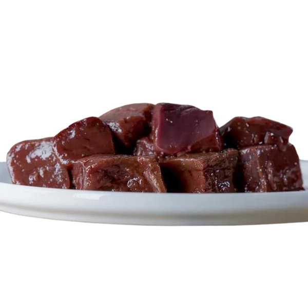 Stücke von Rindeleber auf einem weißen Teller, glänzende Oberfläche, in verschiedenen Größen und Formen, 500g. Marke: Barfgold.