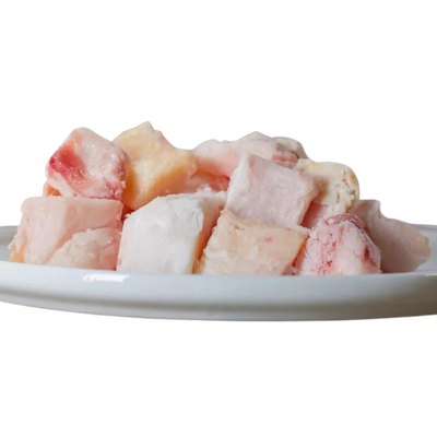 Stücke von Rinderfett in verschiedenen Größen und Farben auf einem weißen Teller. Marke 'Barfgold', 500g. 