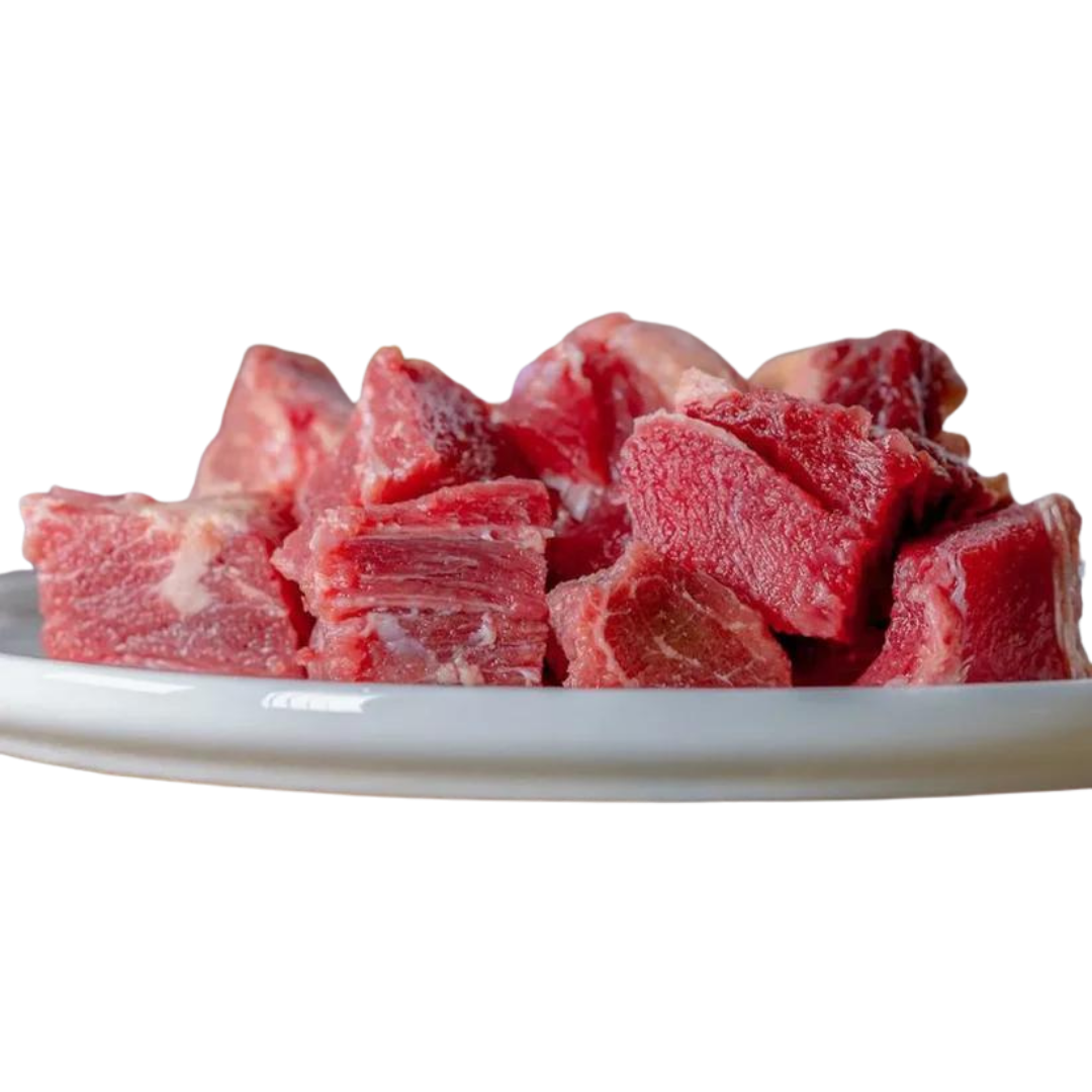 Auf einem weißen Teller liegen grob geschnittene Stücke durchwachsenes Rindfleisch, mit roten Muskelfasern und helleren Fettanteilen, roh und naturbelassen.