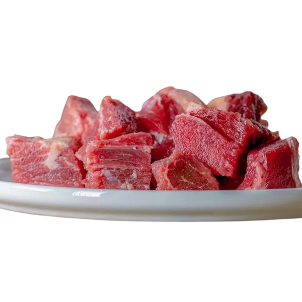 Auf einem weißen Teller liegen grob geschnittene Stücke durchwachsenes Rindfleisch, mit roten Muskelfasern und helleren Fettanteilen, roh und naturbelassen.